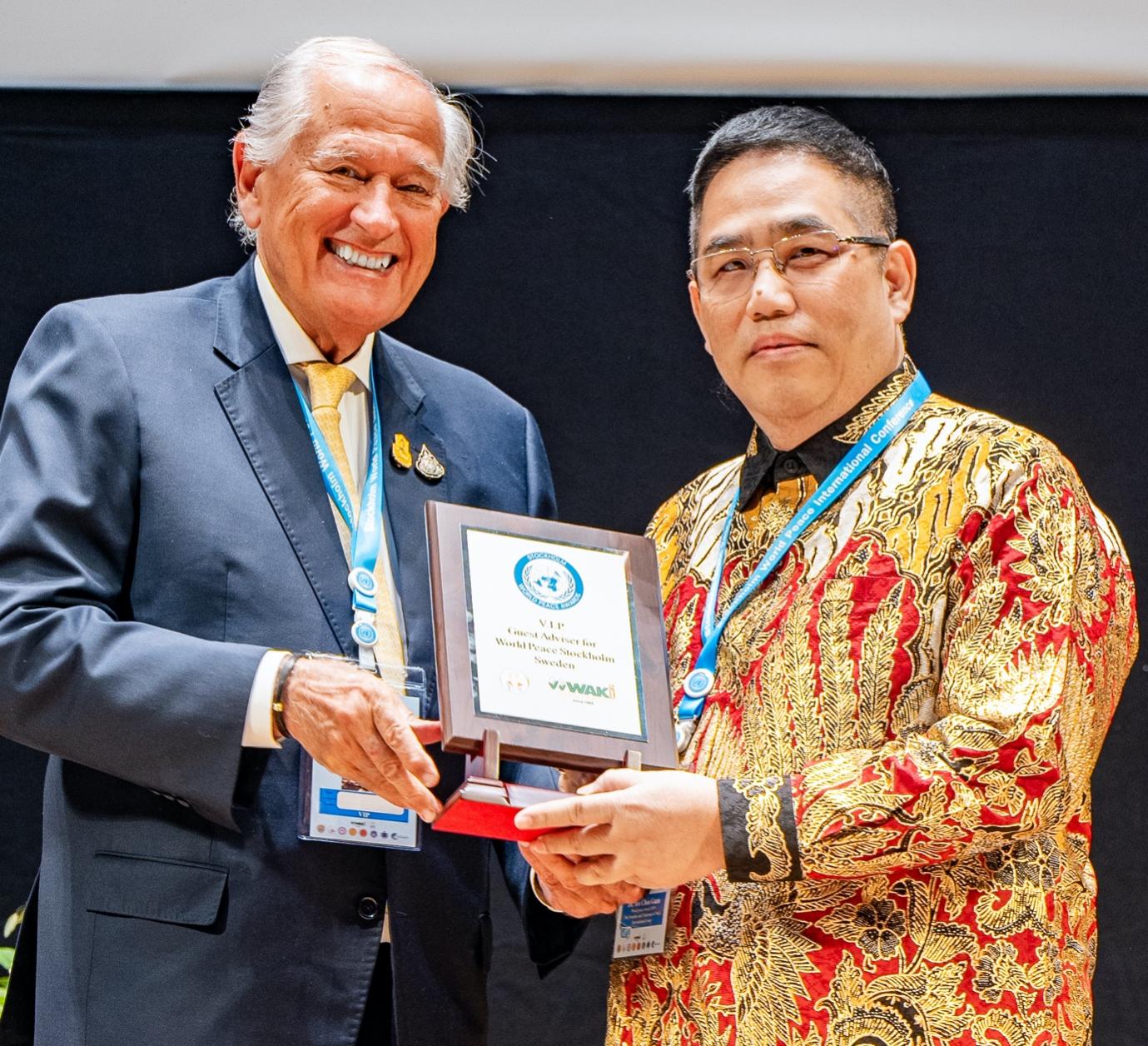 A person holding a plaque with a person in a suit
Description automatically generated